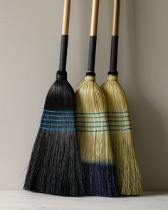 three brooms are lined up against the wall