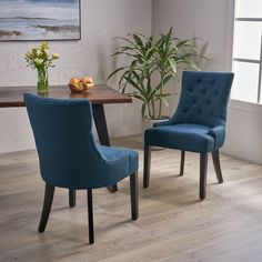 two blue chairs sitting next to each other on a wooden floor in front of a table