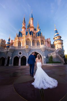 a bride and groom standing in front of the castle at disney's magic kingdom