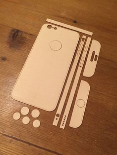 an iphone cut out on top of a wooden table next to some buttons and circles