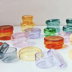 there are many different colored glass containers on the table