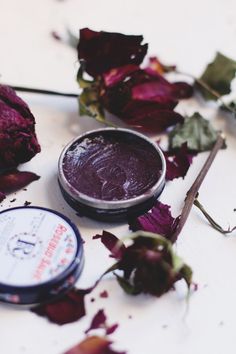 a close up of a flower next to a jar of lip balm