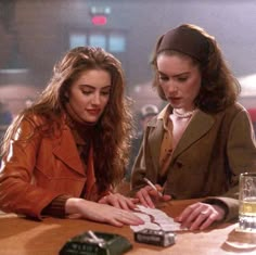 two women sitting at a table with papers