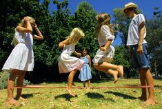 four people jumping over a rope in the grass