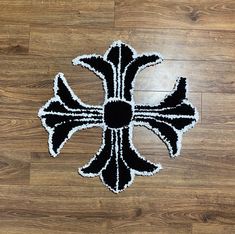 a black and white rug with a cross on the floor in front of wooden floors