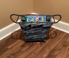 a magazine holder made out of old newspaper and some kind of wire on the floor