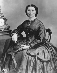 an old black and white photo of a woman sitting at a table with a clock