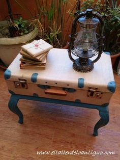 an old suitcase turned into a table with books on it and a lantern in the background