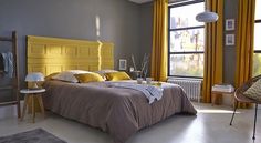 a bed room with a neatly made bed and yellow curtains