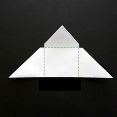 an origami paper airplane on a black surface with green lines going through it