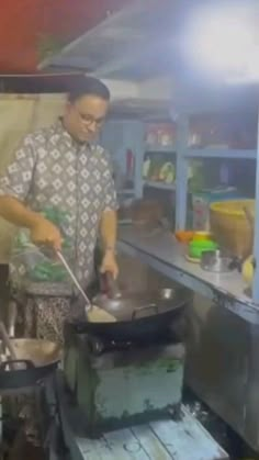 a man cooking food in a wok on top of a stove