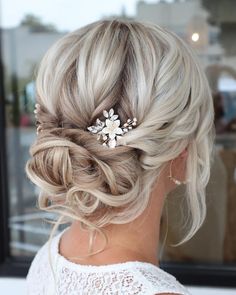 the back of a woman's head with blonde hair and a flower in her hair