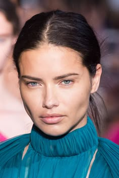 a close up of a woman's face with blue eyes and hair in a ponytail