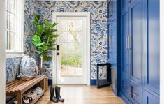 a blue and white entryway with wallpaper, wood flooring and wooden bench