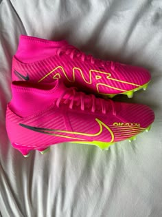 a pair of pink and yellow nike soccer cleats on a white bed sheet