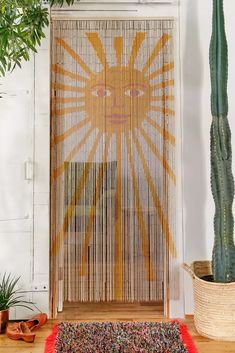 a room with a rug, potted plants and a curtain in the background that has an orange sun design on it