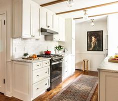 a kitchen with white cabinets and wood floors