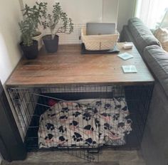 a dog crate under a table with a blanket on it and a laptop sitting on top