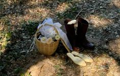 a pair of brown boots sitting on the ground next to a basket with white flowers