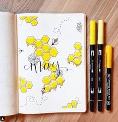 an open notebook with yellow honeycombs and two black marker pens on the page