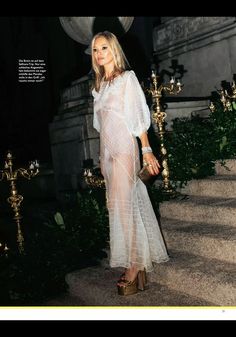 a woman in a sheer white dress is standing on some steps and posing for the camera