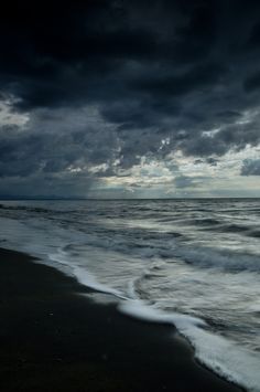 the sky is dark and cloudy over the ocean