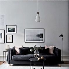 a living room filled with black furniture and pictures on the wall above it's coffee table