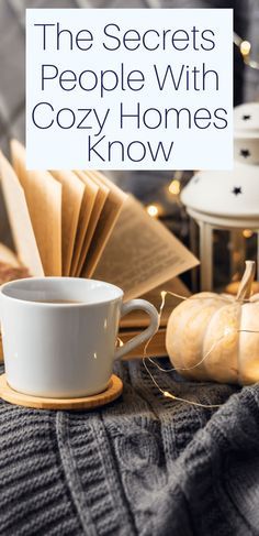 a cup of coffee sitting on top of a table next to an open book and some pumpkins