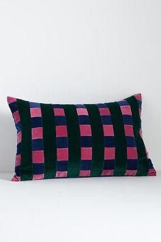 a black and pink pillow sitting on top of a white bed next to a wall