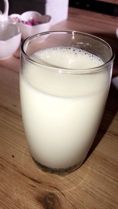 a glass of milk sitting on top of a wooden table