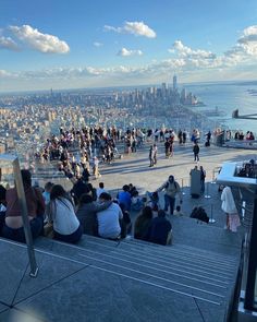 many people are sitting and standing on the top of a building looking out at the city