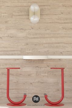 a red chair sitting on top of a wooden floor next to a white table and lamp