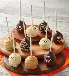 cake pops decorated with halloween decorations on a wooden platter