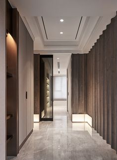 an empty hallway with wood paneling on the walls and white tile floors, along with recessed lighting