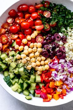 a white bowl filled with lots of different types of vegetables and veggies in it