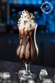 an ice cream sundae with chocolate sauce and whipped cream in a glass on a table