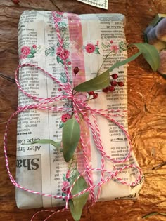 a piece of paper wrapped in pink and green string with flowers on it sitting on top of a wooden table