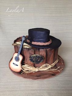 a cake made to look like a tree stump with a guitar and hat on top