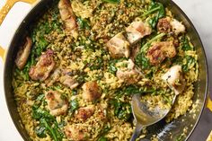 a skillet filled with rice, chicken and spinach on top of a table