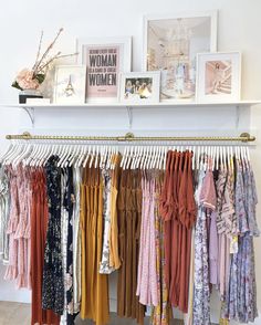 a rack full of women's clothing hanging on clothes racks in front of a white wall