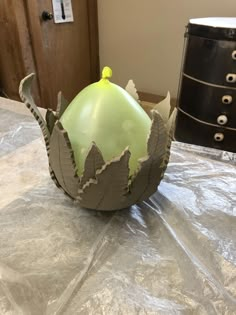 a green vase sitting on top of a table covered in plastic wrap and silver foil