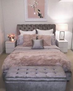 a bedroom with a bed, ottoman and pictures on the wall above it that is decorated in pink and grey tones