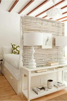 a bedroom with white walls and wooden slats on the wall, along with two lamps