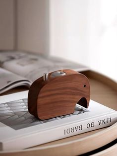 an elephant shaped wooden object sitting on top of a white laptop computer next to a book