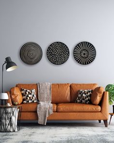 a living room with three circular metal wall art pieces on the wall and a brown leather couch