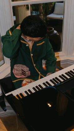 a young boy sitting at a piano with his hands on his head while playing the piano