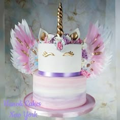 a white cake with pink and purple frosting, topped with an unicorn's horn