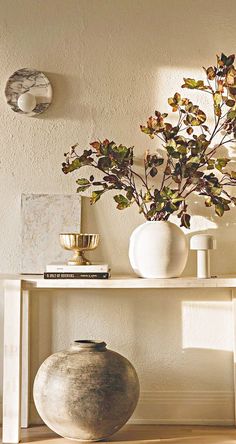 vases and other decorative items sit on a shelf in front of a white wall