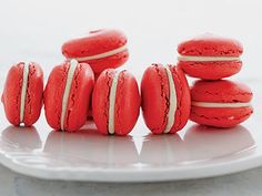 red macaroons are arranged on a white plate