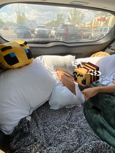 a woman laying in the back seat of a car with pillows on top of it